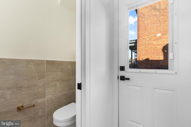 bathroom featuring tile walls and toilet