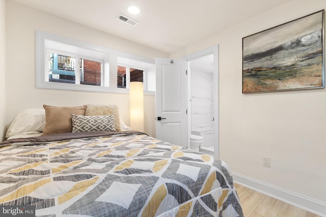 bedroom featuring connected bathroom and wood-type flooring