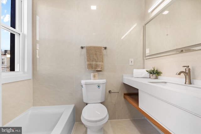 bathroom featuring tile walls, vanity, a tub, and toilet