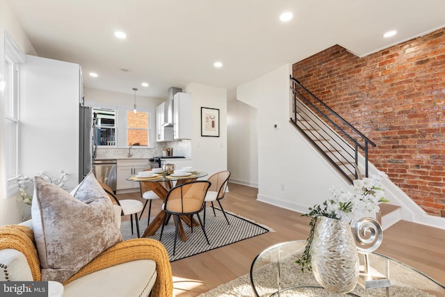 dining room with brick wall, sink, and light hardwood / wood-style floors