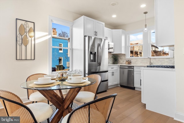 kitchen featuring white cabinetry, pendant lighting, stainless steel appliances, and light hardwood / wood-style floors