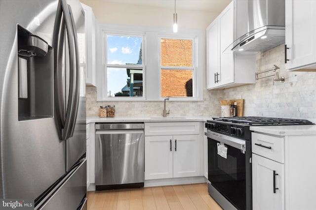 kitchen with white cabinetry, appliances with stainless steel finishes, sink, and exhaust hood