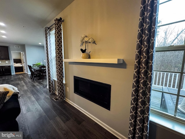 living area with recessed lighting, visible vents, baseboards, dark wood-style floors, and a glass covered fireplace