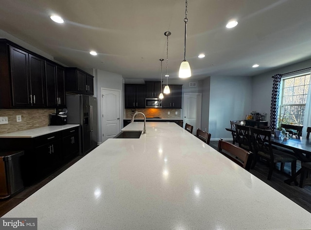 kitchen with stainless steel microwave, a sink, black fridge with ice dispenser, and dark cabinets