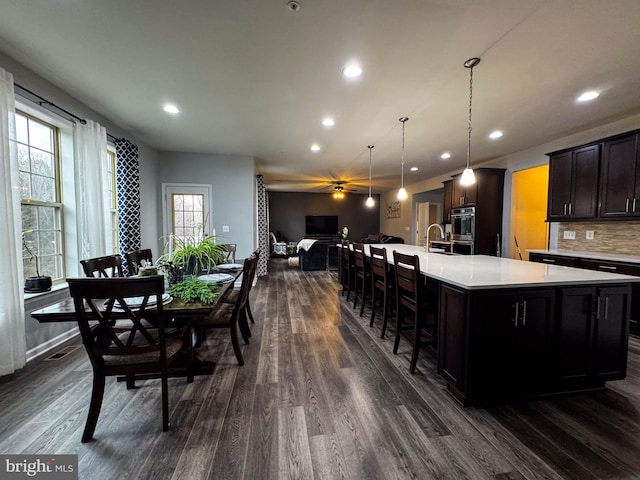 kitchen featuring a large island, open floor plan, dark wood-type flooring, light countertops, and backsplash