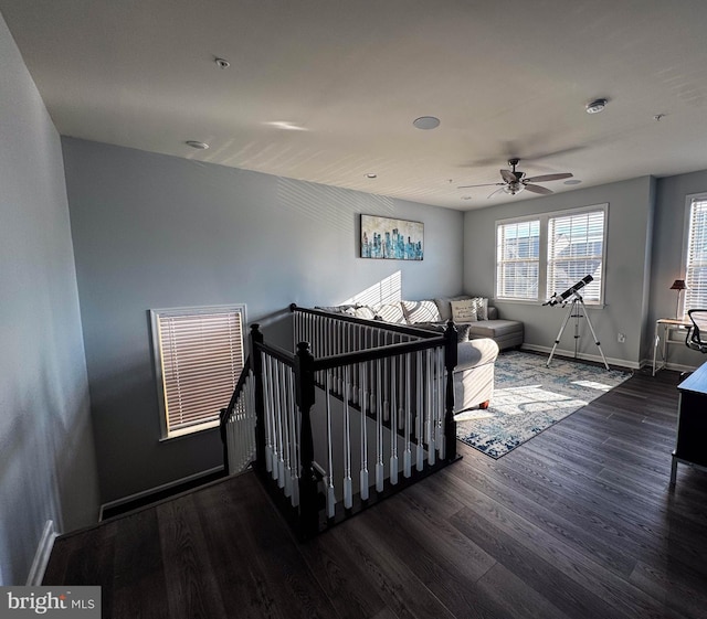 interior space featuring a ceiling fan, baseboards, and wood finished floors