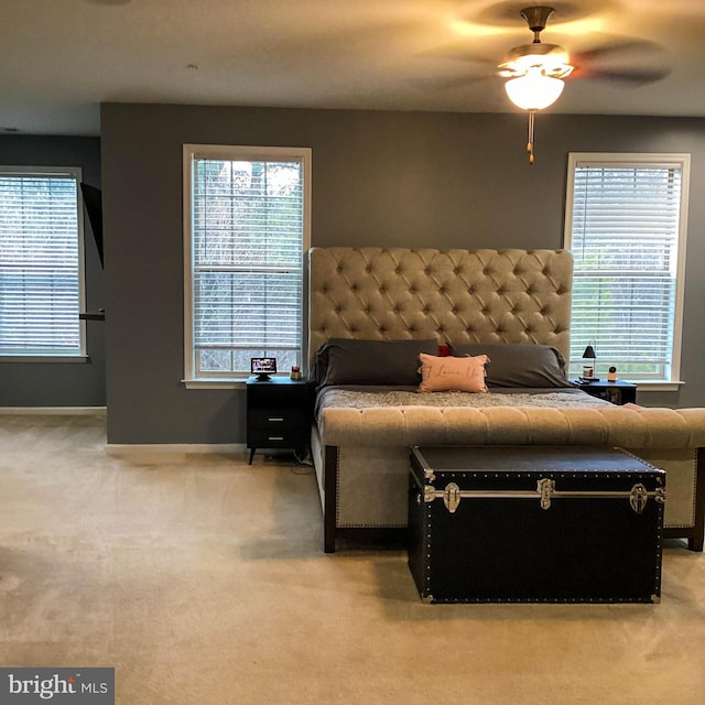 bedroom with light carpet, ceiling fan, multiple windows, and baseboards