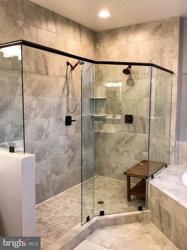 bathroom with a tile shower and a bath