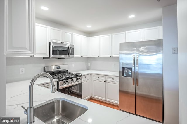 kitchen with light stone counters, sink, stainless steel appliances, and white cabinets