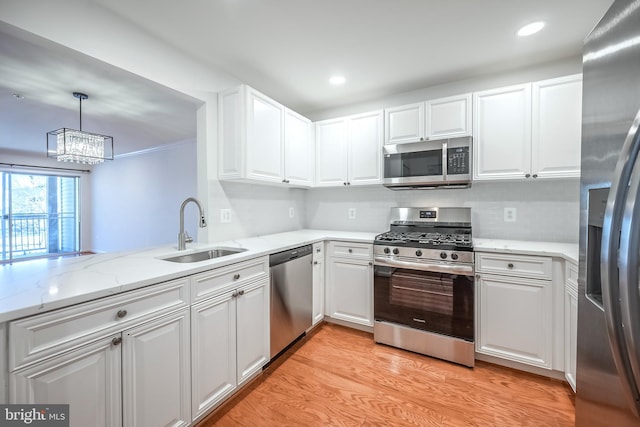 kitchen featuring sink, appliances with stainless steel finishes, white cabinets, decorative light fixtures, and kitchen peninsula