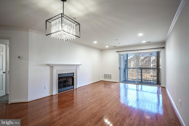 unfurnished living room with wood-type flooring, ornamental molding, and a notable chandelier