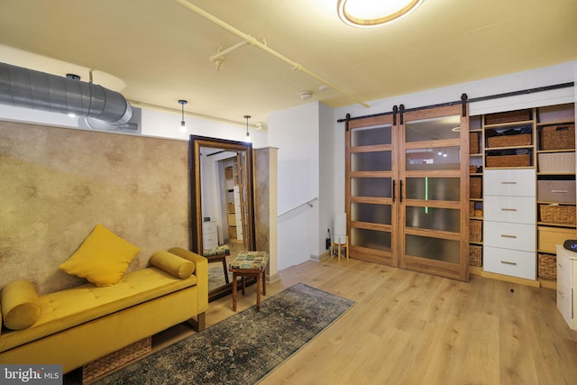 living area featuring a barn door and light hardwood / wood-style floors