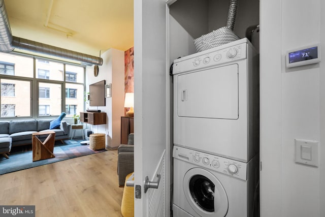 clothes washing area featuring stacked washer and clothes dryer and hardwood / wood-style floors