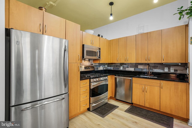 kitchen with sink, decorative backsplash, stainless steel appliances, and light wood-type flooring