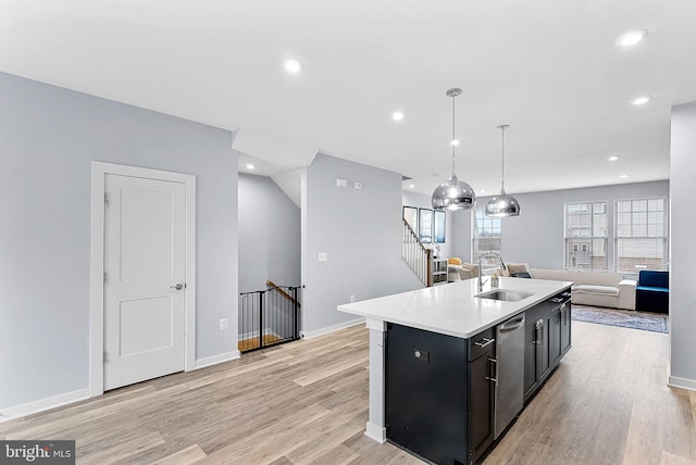 kitchen featuring a sink, open floor plan, light countertops, hanging light fixtures, and dishwasher