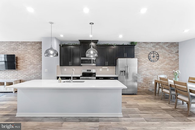 kitchen featuring appliances with stainless steel finishes, pendant lighting, light countertops, and a sink