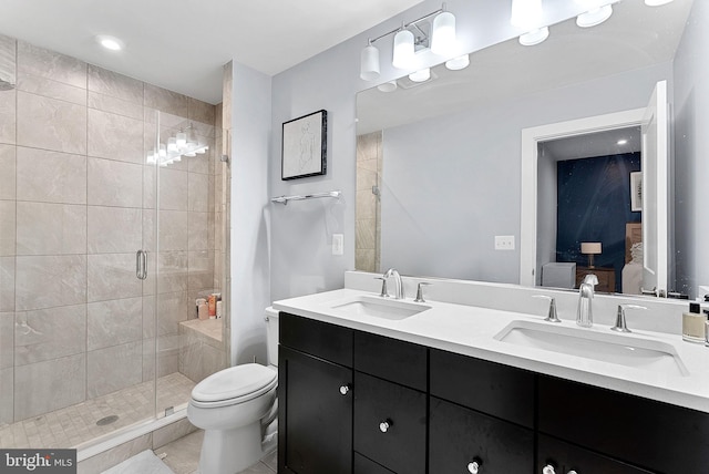 bathroom with a stall shower, a sink, toilet, and double vanity