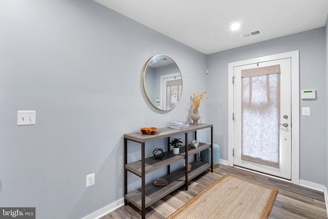 foyer entrance with visible vents, dark wood finished floors, and baseboards