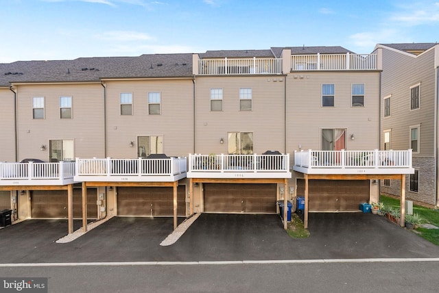 back of house featuring driveway, a balcony, and a residential view