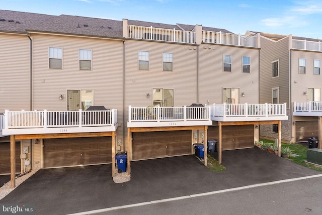 back of property with driveway, a balcony, and an attached garage