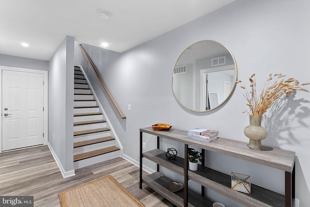 foyer entrance featuring stairway, baseboards, visible vents, and wood finished floors