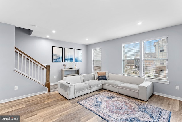 living area featuring light wood-type flooring, stairs, baseboards, and recessed lighting