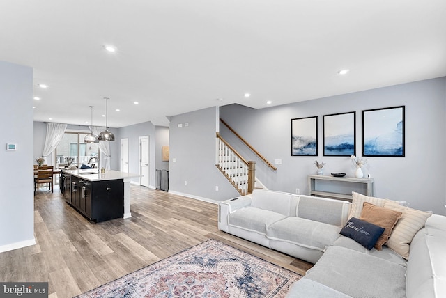 living area featuring light wood-style floors, stairs, baseboards, and recessed lighting