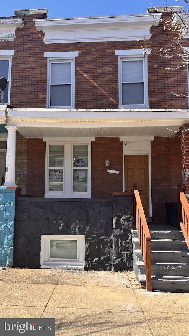 entrance to property featuring a porch and brick siding