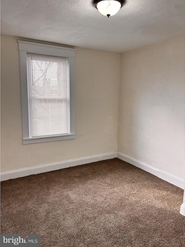 carpeted spare room with baseboards and a textured ceiling