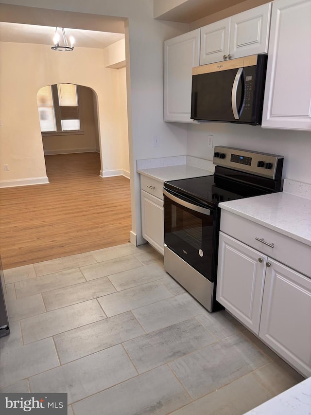 kitchen with arched walkways, baseboards, white cabinets, appliances with stainless steel finishes, and wood tiled floor