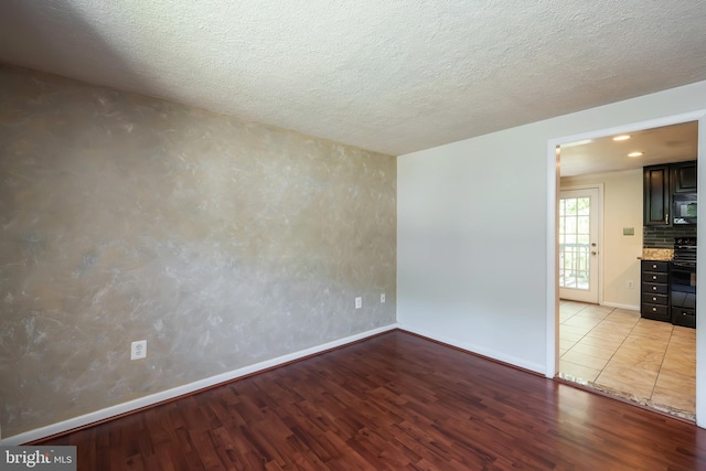 empty room with a textured ceiling and light wood-type flooring