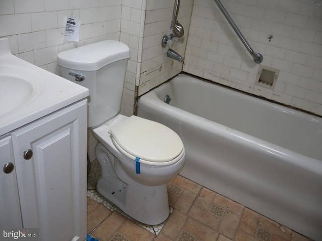 full bathroom featuring tiled shower / bath, vanity, toilet, and tile walls