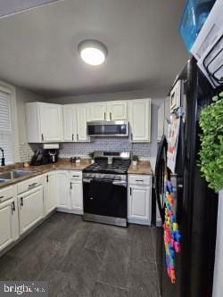 kitchen featuring tasteful backsplash, white cabinetry, appliances with stainless steel finishes, and sink