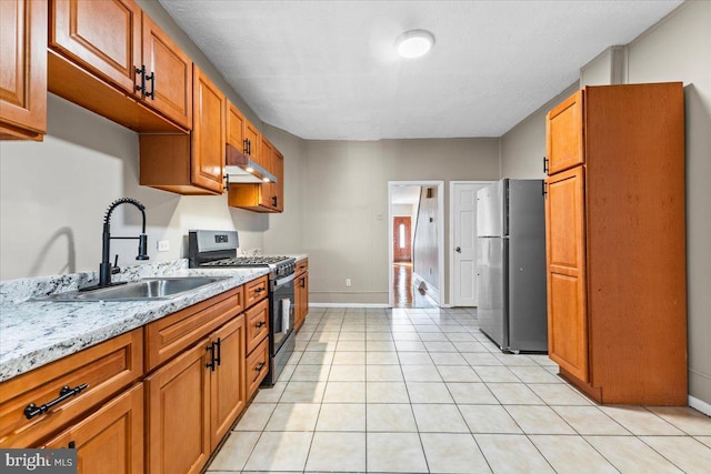 kitchen with light stone counters, appliances with stainless steel finishes, sink, and light tile patterned floors