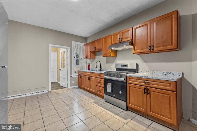 kitchen with sink, stainless steel gas range oven, light stone countertops, a textured ceiling, and a baseboard radiator