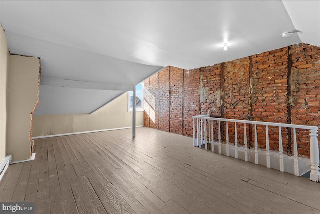 bonus room with lofted ceiling, wood-type flooring, and brick wall