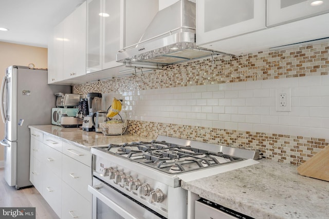 kitchen featuring extractor fan, white cabinetry, stainless steel appliances, light stone countertops, and decorative backsplash