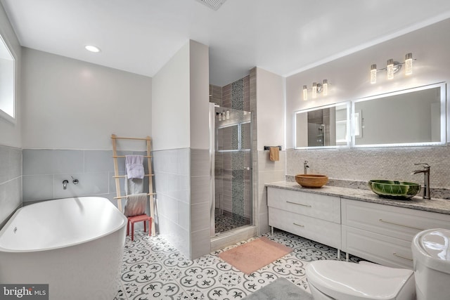 full bathroom featuring tile patterned floors, toilet, tile walls, vanity, and independent shower and bath