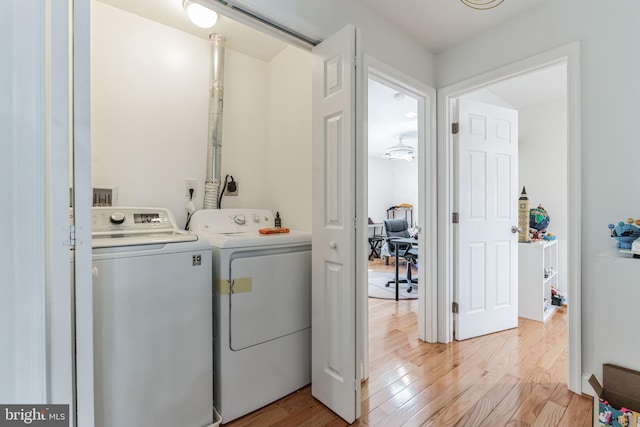 laundry room with washing machine and clothes dryer and light hardwood / wood-style flooring