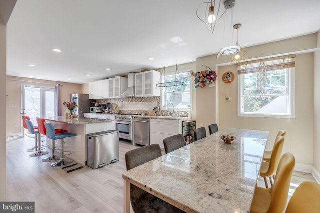 kitchen with decorative light fixtures, a center island, appliances with stainless steel finishes, a kitchen breakfast bar, and white cabinets