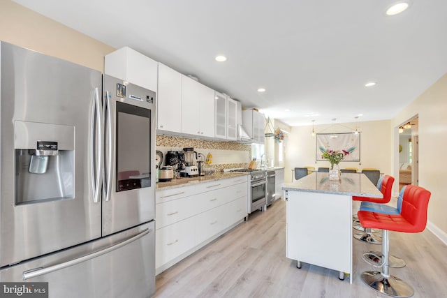 kitchen featuring appliances with stainless steel finishes, a kitchen bar, a kitchen island, and white cabinets