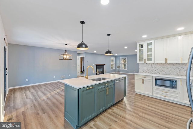 kitchen featuring pendant lighting, white cabinetry, sink, a kitchen island with sink, and stainless steel appliances