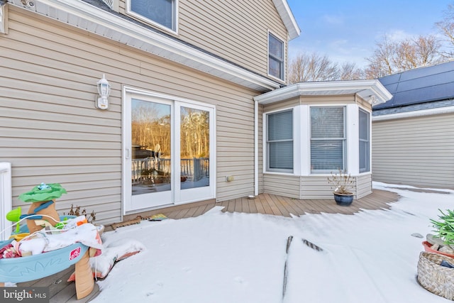 snow covered property entrance with a wooden deck