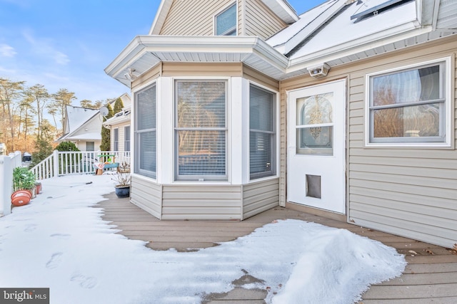 snow covered property entrance with a deck