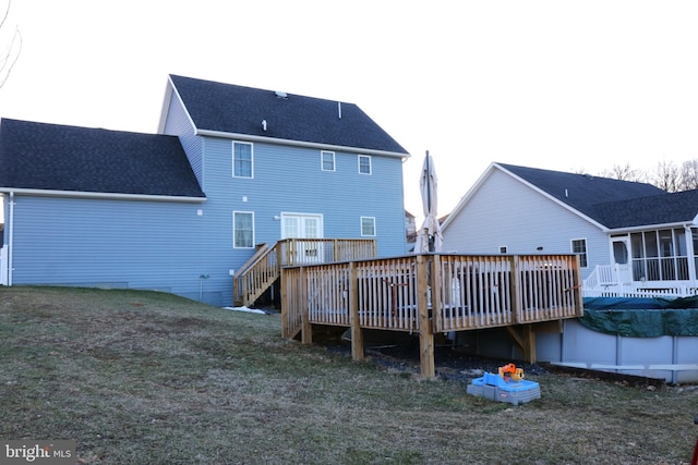 back of property featuring a pool side deck and a lawn