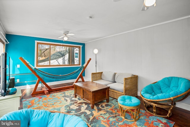 living room with wood-type flooring, ornamental molding, and ceiling fan