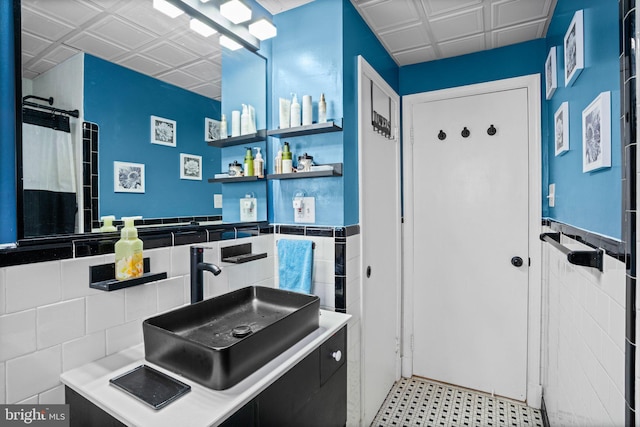 bathroom with walk in shower, sink, and tile walls