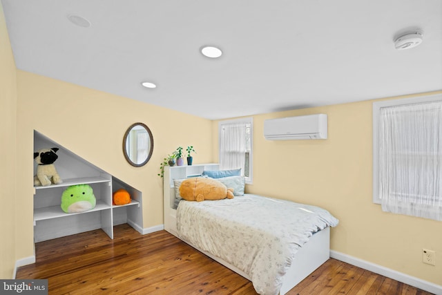 bedroom with hardwood / wood-style flooring and a wall unit AC