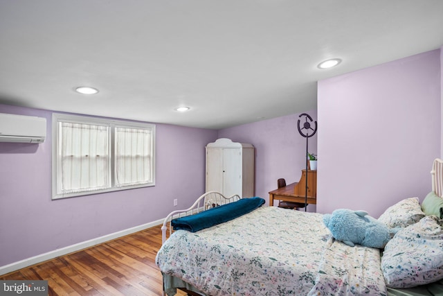 bedroom featuring hardwood / wood-style floors and a wall unit AC