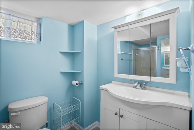 bathroom with vanity, a shower with door, and toilet